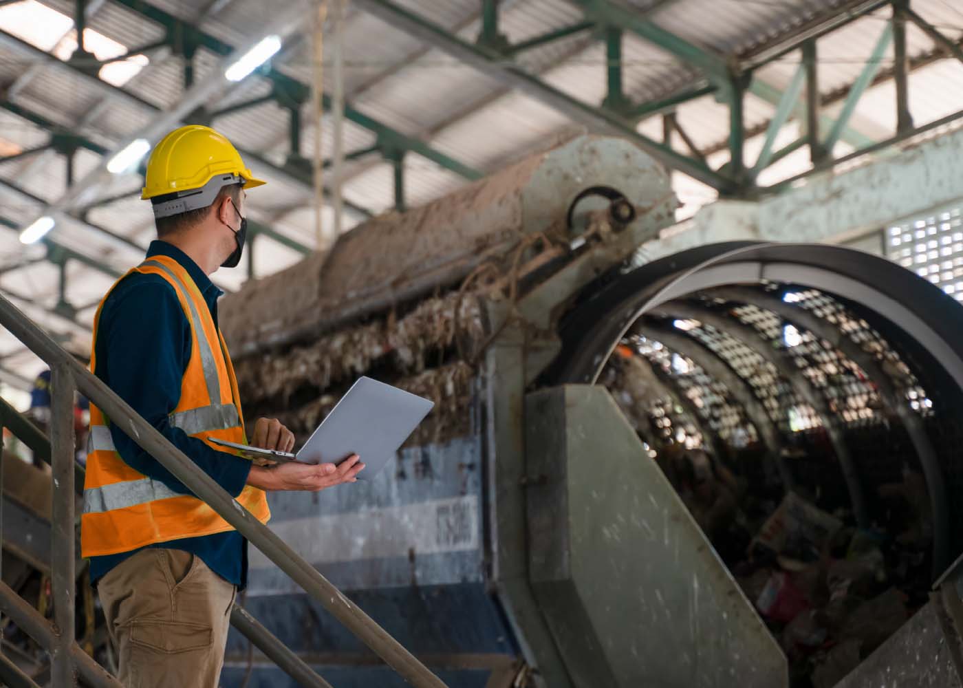 Construction worker in a hard hat holding a computer inspecting materials.