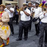 Screenshot band members playing instruments in small indoor parade in New Orleans